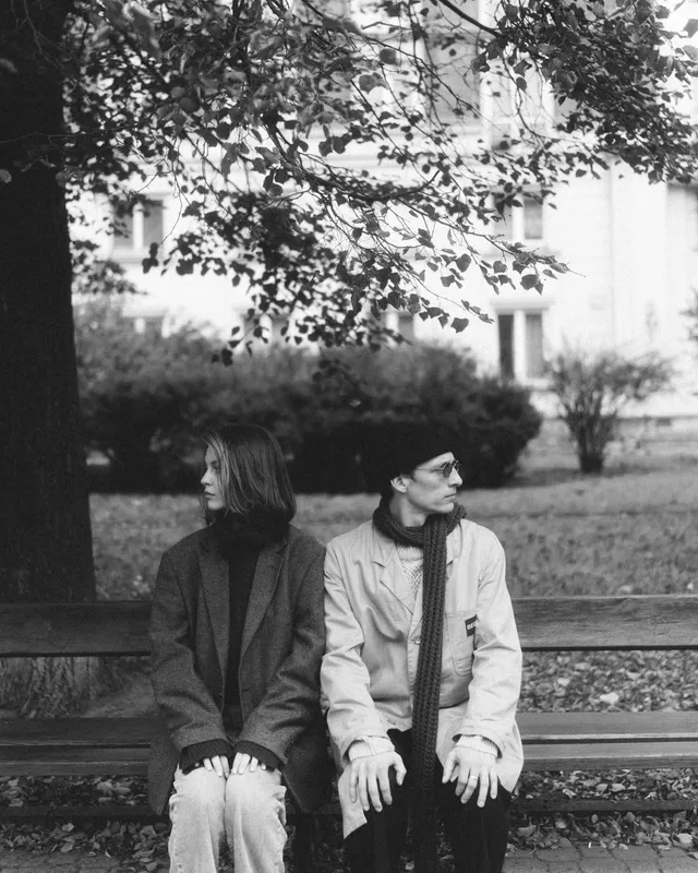 Black and white: the two of them sitting on a park bench, looking opposite ways