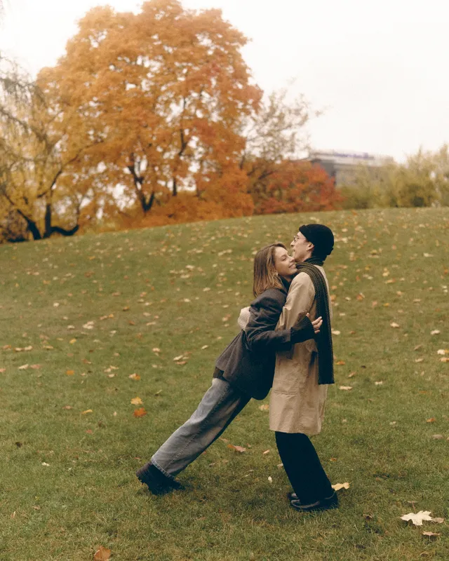 Sergei lifting Elvira in a park with orange autumn trees