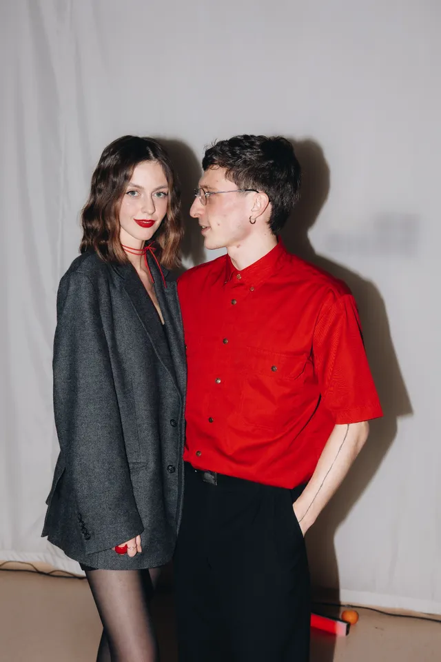 Studio portrait: Elvira in a grey blazer and Sergei in a red shirt