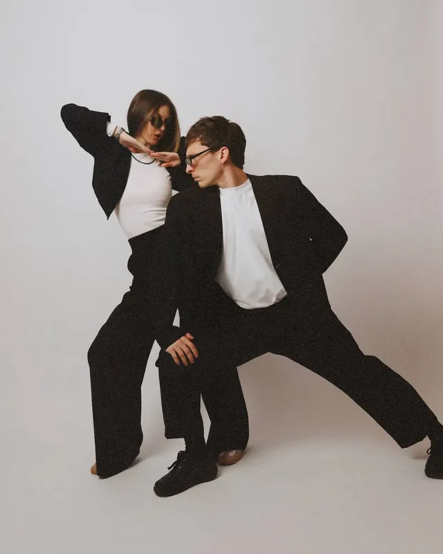 Studio shot: both in black suits, mid-pose