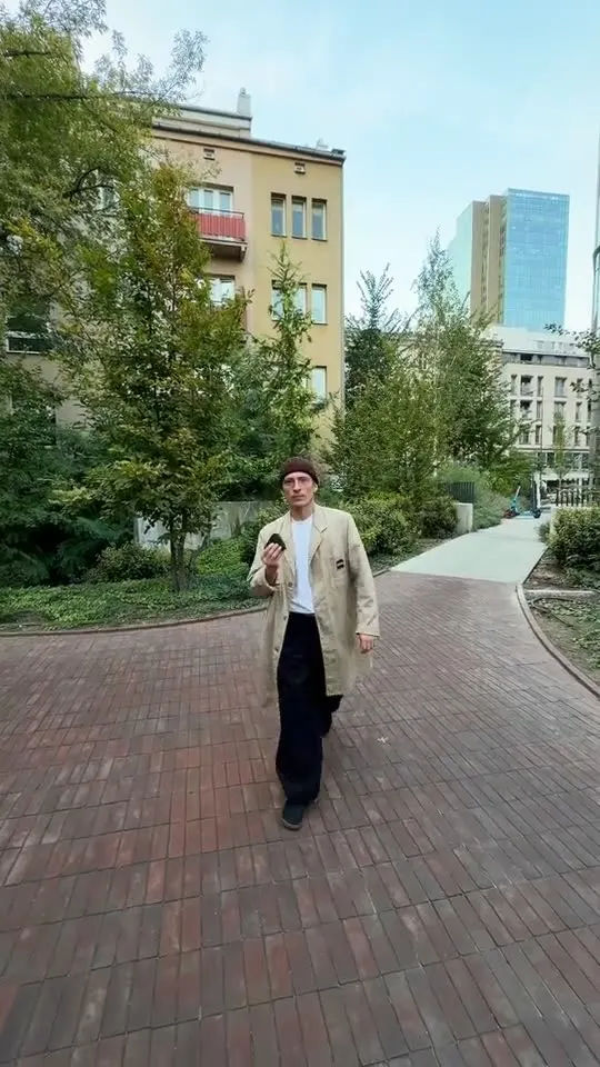 Sergei in a beanie on a city sidewalk, a hand reaching toward the camera