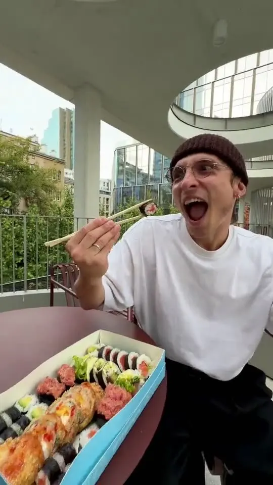 Sergei in a beanie, shouting with joy at a cafe table