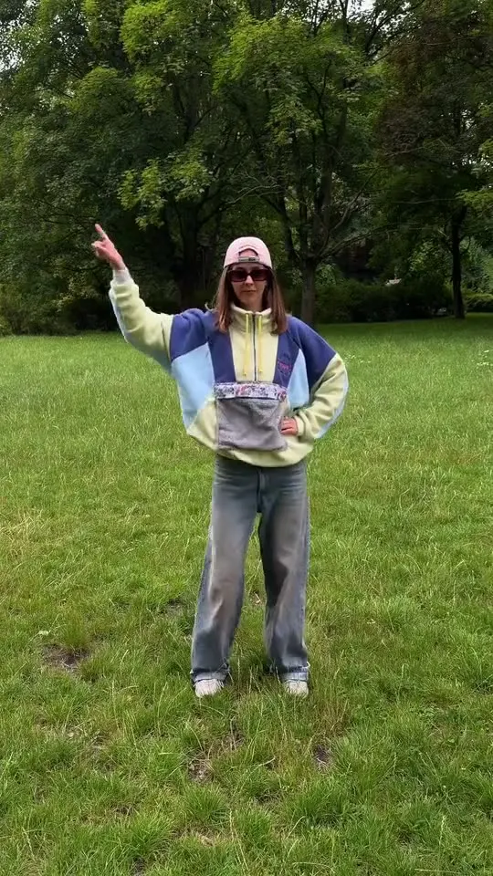 Elvira in a pastel sweater and pink cap dancing on the grass
