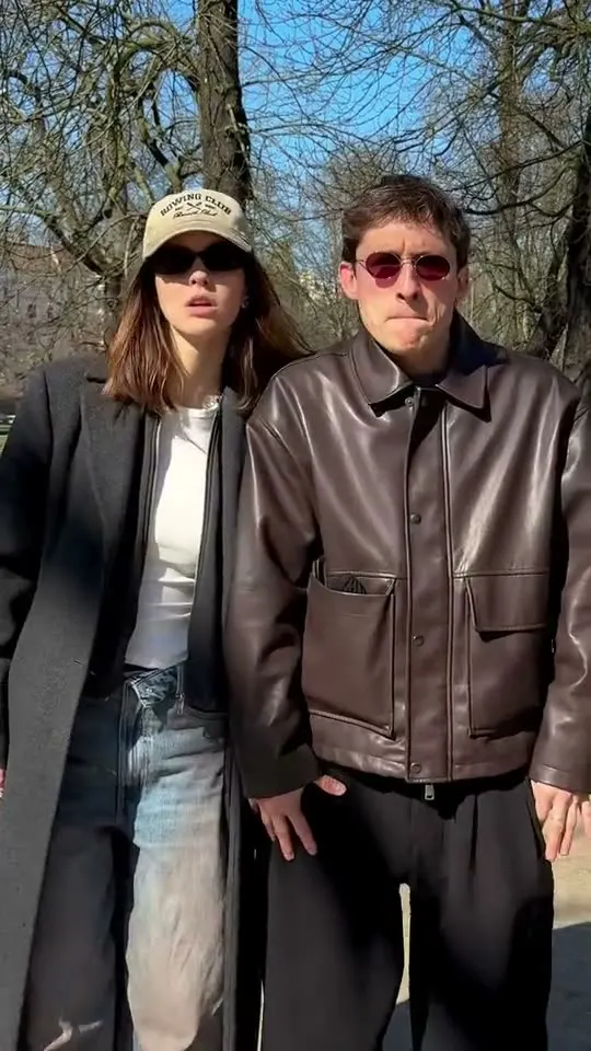 Sergei and Elvira in long coats and sunglasses, pointing at the camera