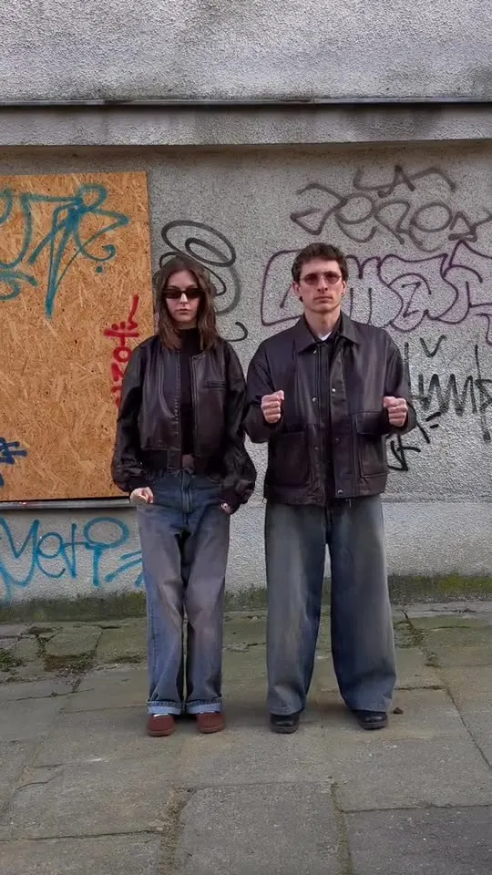 Sergei and Elvira face to face by a boarded-up wall covered in tags